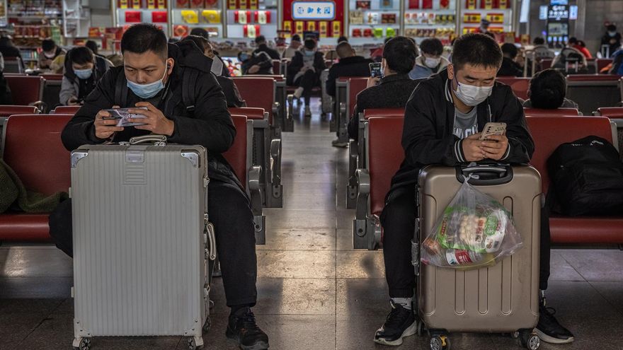 Passengers wearing protective face masks use their mobile phones as they wait with their luggage at the Beijing West railway station amid the coronavirus pandemic in Beijing, China, 17 November 2021.