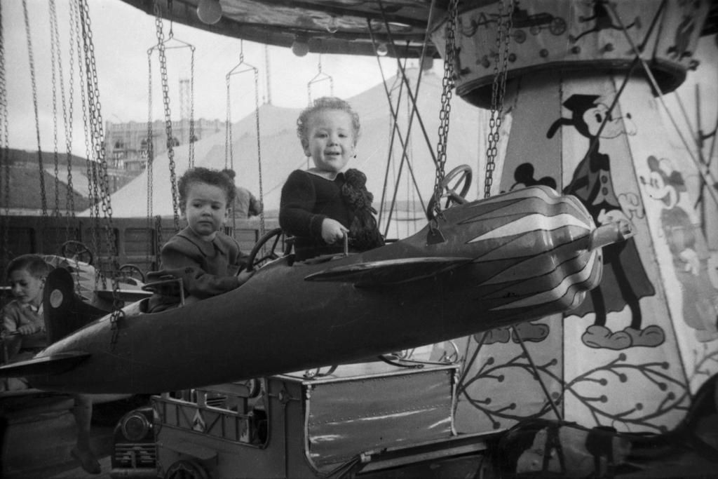 Los dos niños subidos en el avión de un carrusel en 1951