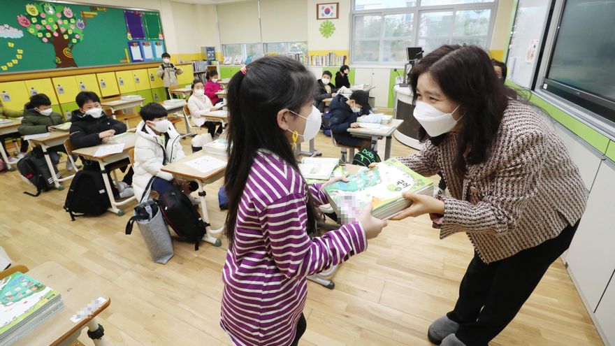 Una maestra da libros de texto a su estudiante en una escuela primaria en Sejong, Corea del Sur. Escuelas en todo el país reabrieron en medio de la pandemia de coronavirus. EFE/EPA/YONHAP