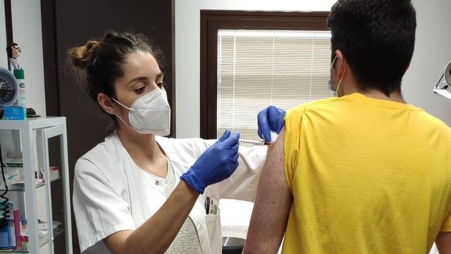 Una trabajadora sanitaria vacuna a un joven.