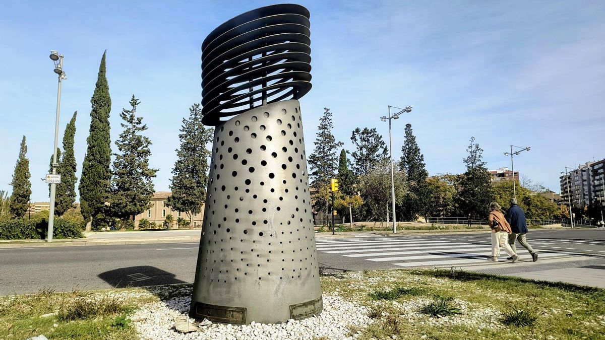 Respiradero del túnel bajo la Avenida Soria en Zaragoza y pareja caminando para alargar la vida contra el cierzo.