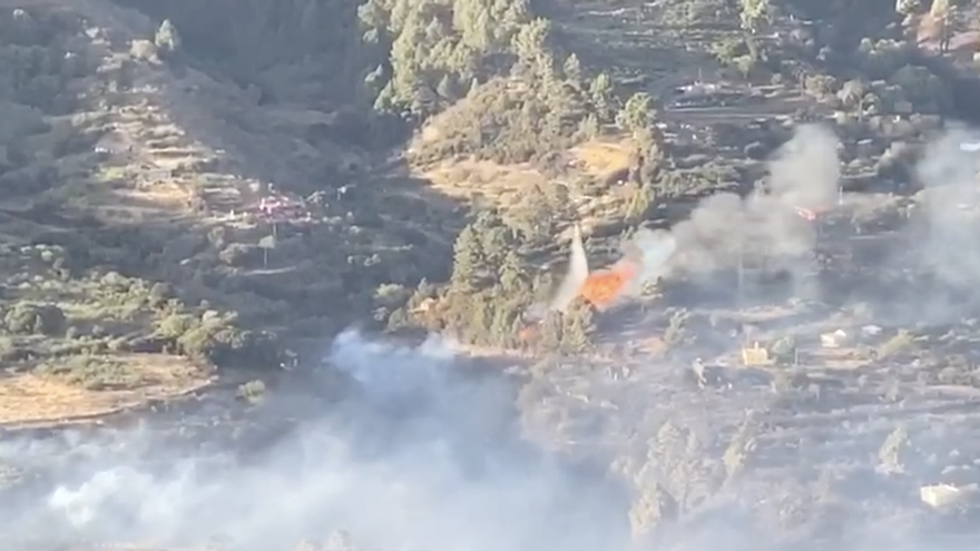 Un helicóptero  descarga agua  este domingo sobre las llamas del foco en Lomo de Las Palomas del incendio de Garafía. Imagen captada de  un vídeo de la Guardia Civil.