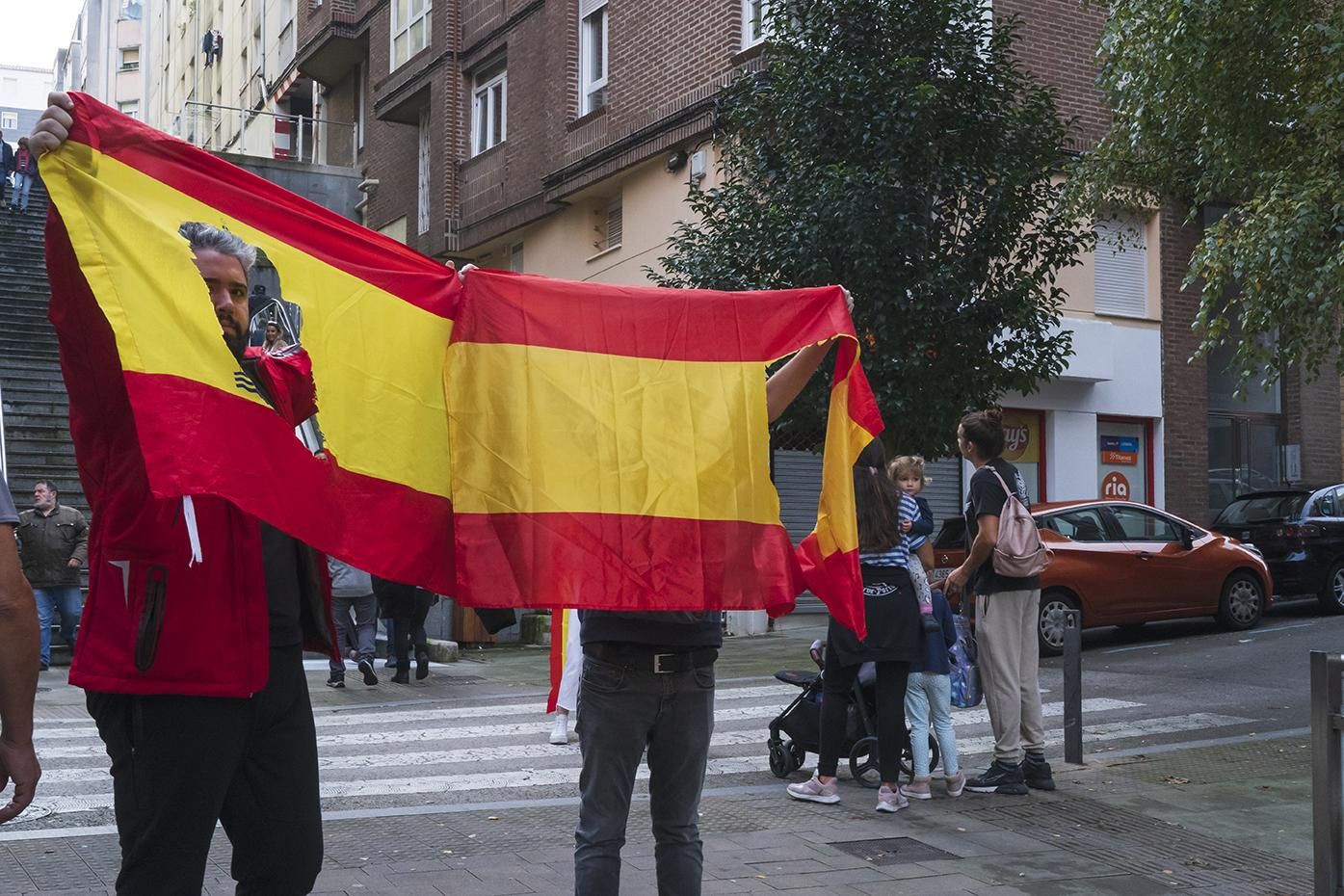 Un manifestante con una bandera con el escudo constitucional recortado como crítica a la monarquía.