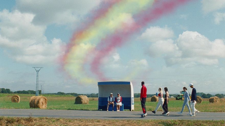 Dos ancianos y un grupo de jóvenes en una parada de autobús en una aldea de Galicia