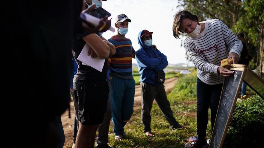Una voluntaria enseña algunas frases en español a un grupo de inmigrantes en el exterior del campamento Las Raíces