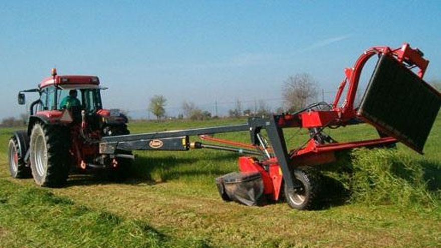 Un tractor trabaja con maquinaria agrícola en el campo.