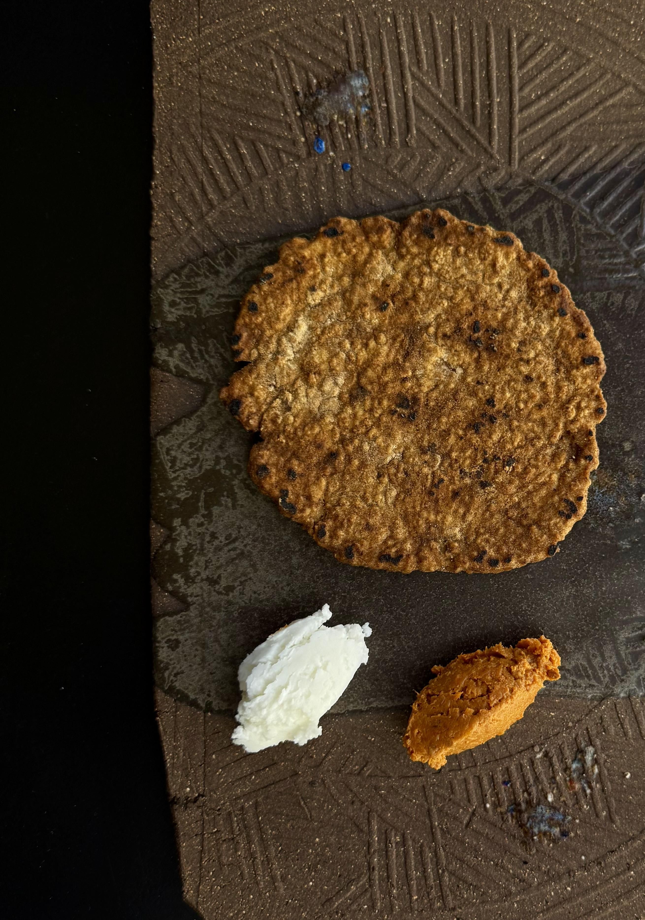 Gaite de tofe de gofio de cebada. Se acompaña de sobrada vegetal y mantequilla de cabra, elaborada con el lácteo que usaban los aborígenes para hacer la leche mecida y la mantequilla clarificada.