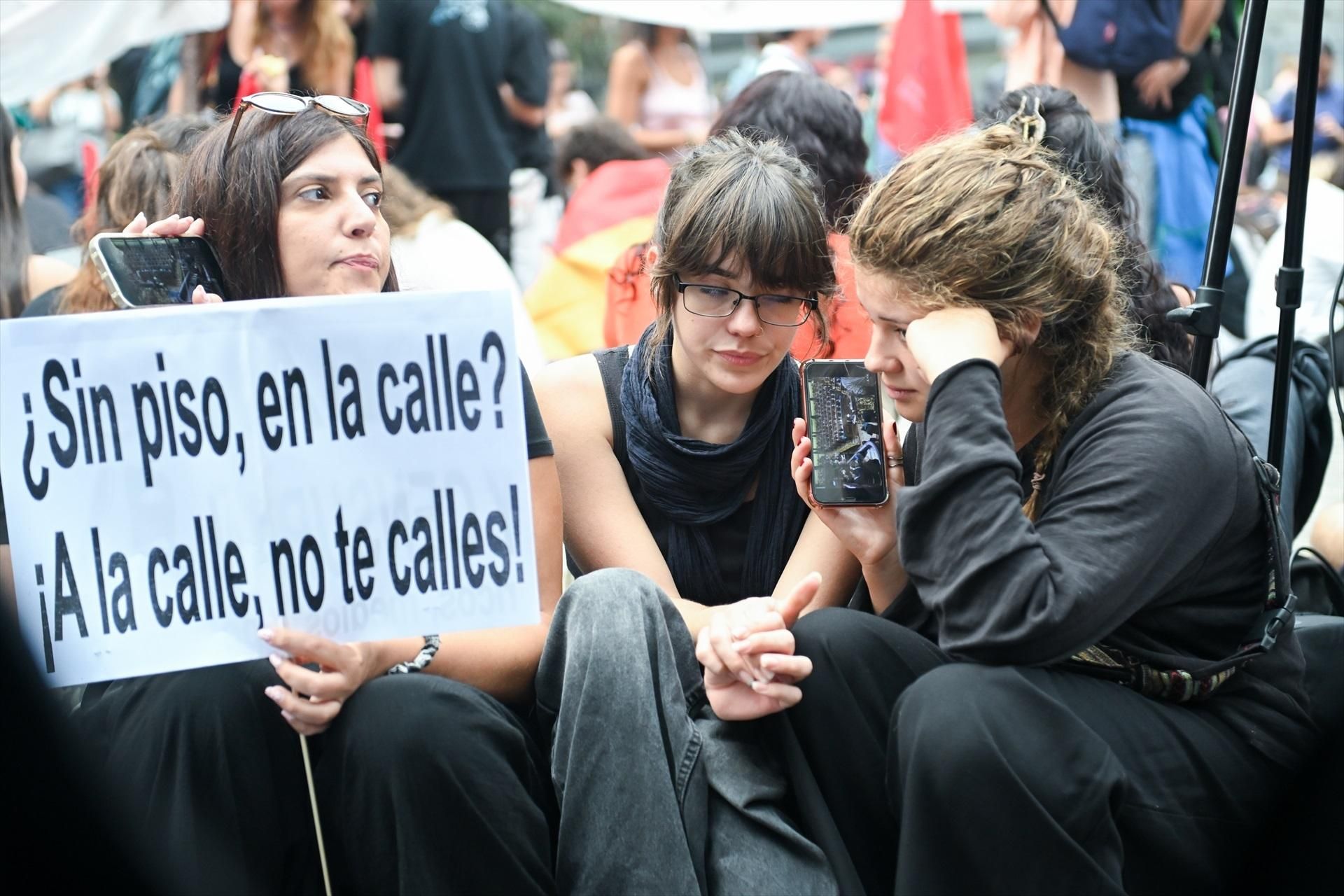 Tres jóvenes siguen desde sus móviles la votación en el Congreso