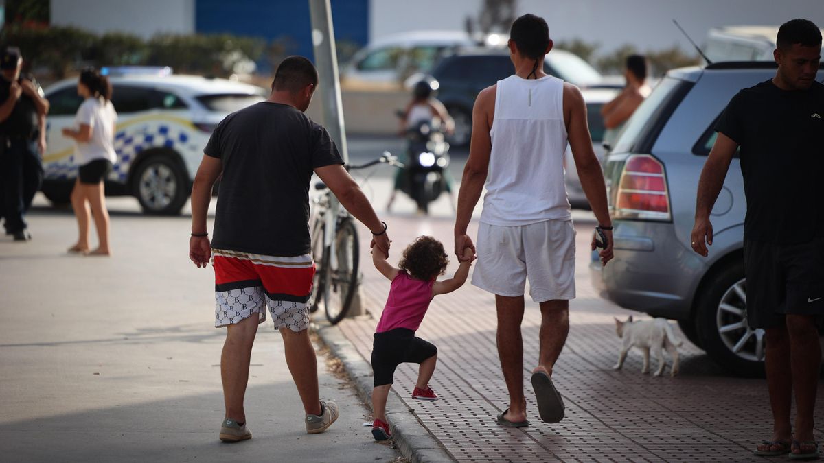 Dos hombres sujeran a una niña pequeña de la mano mientras abandonan el poblado chabolista