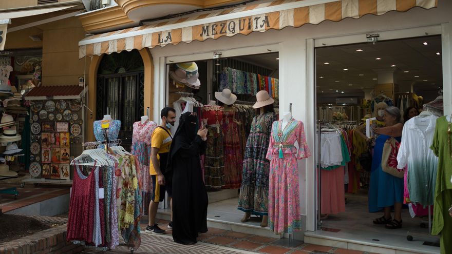 Una turista toma un video de ropa en un establecimiento del casco antiguo de Marbella. 