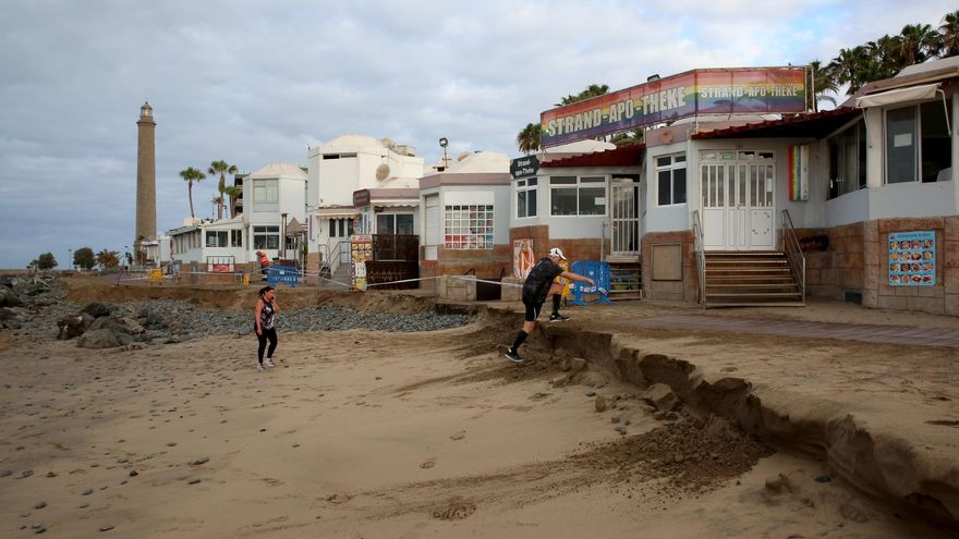 Una persona sube el talud formado como consecuencia de la pleamar que se llevó la arena que sostenía parte del paseo entre el Faro y la Charca de Maspalomas.