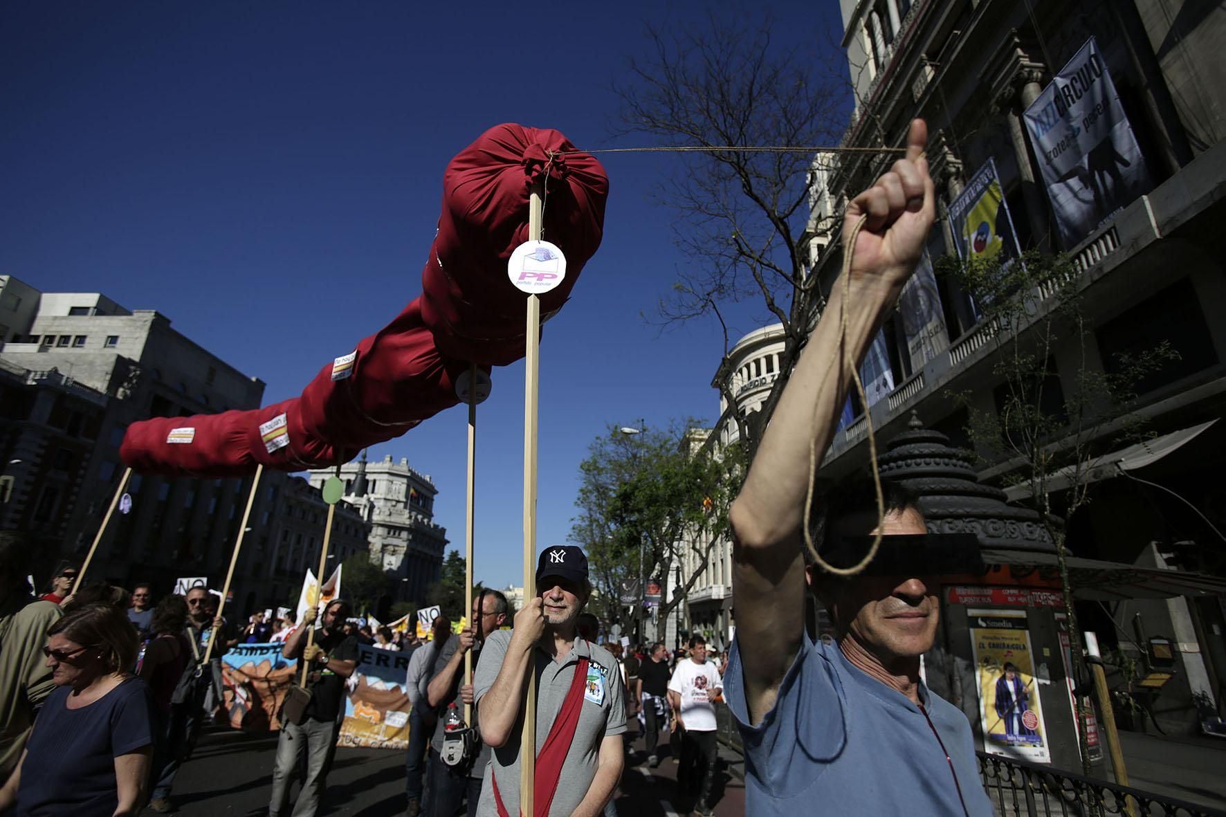 Un grupo de manifestantes cargan con una simulación de un chorizo, símbolo de uno de los lemas del 15M. / Olmo Calvo.