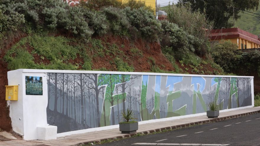 Mural en Caideros de Gáldar, encargado por el Ayuntamiento en 2019 tras los incendios sufridos en la zona. "La palabra fuerza con todo verde en su interior en medio del paisaje desolado dejado por el fuego como homenaje a nuestros campos y gentes", puede leerse en la placa.