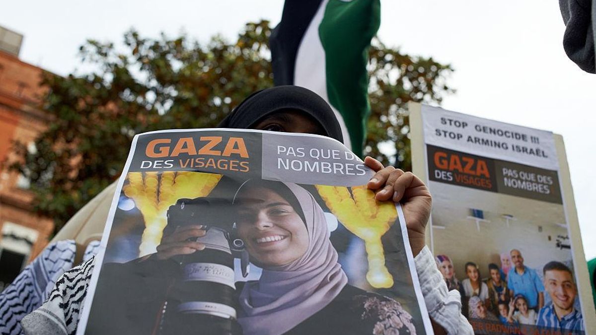 Una mujer muestra el retrato de una periodista palestina asesinada en Gaza durante una protesta en Toulouse, Francia, el 15 de mayo.