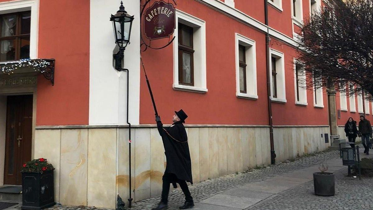Viste capa negra y sombrero y cada día recorre el casco histórico de esta ciudad polaca para encender más de 100 lámparas de gas
