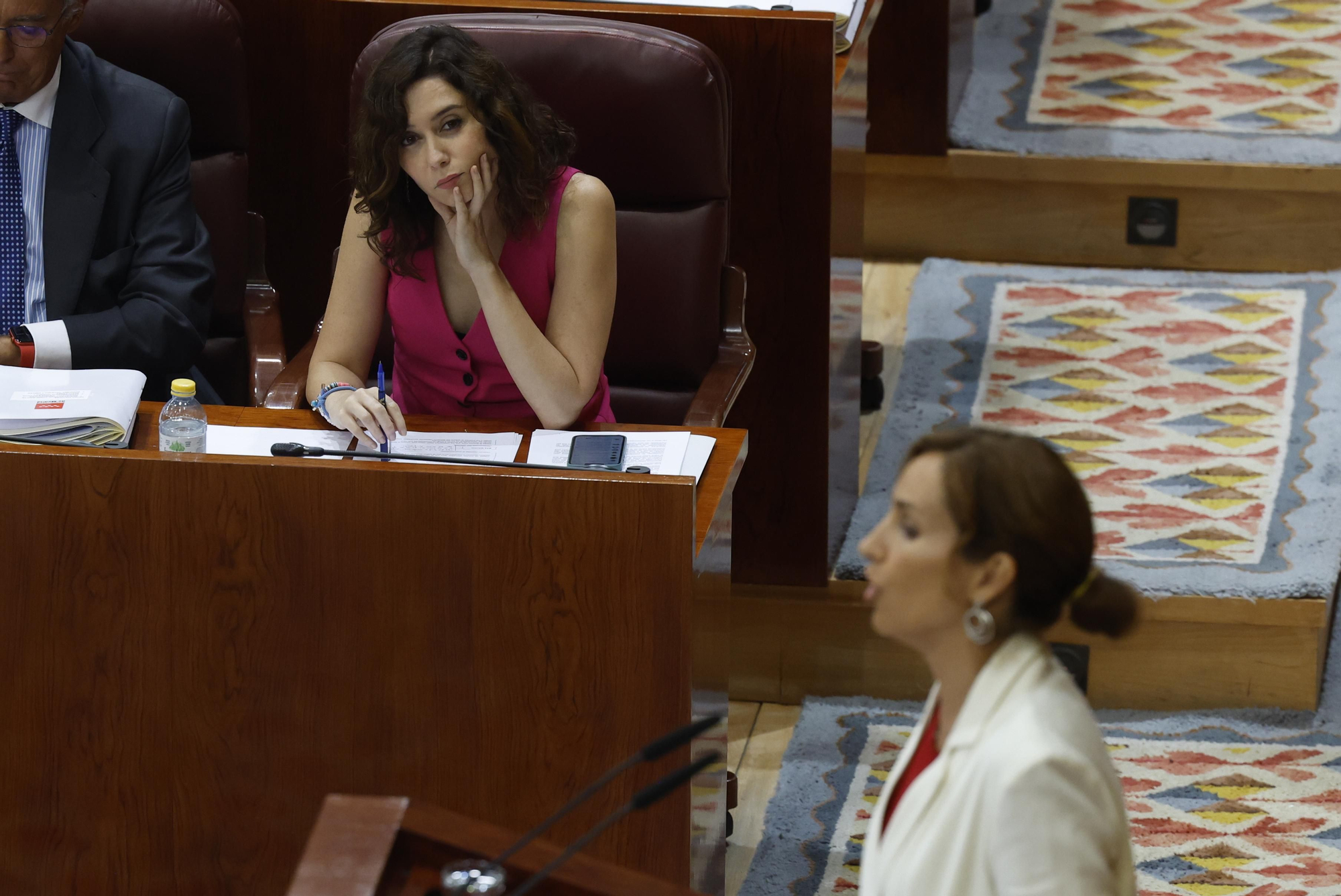 Una imagen muy poco habitual en el pleno. Díaz Ayuso mira a la cara a Mónica García, y no a sus papeles, durante su intervención.