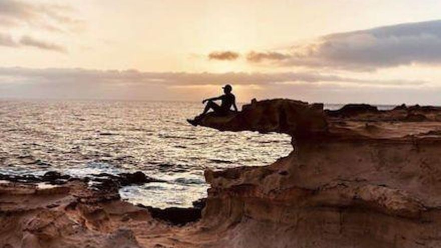 Una persona sentada en el borte de la denominada 'roca cocodrilo' en una imagen publicada en redes sociales.