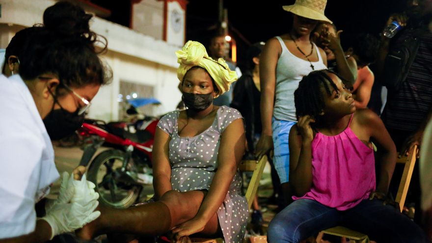 Una mujer migrante haitiana es tratada por una activista sanitaria en México por una herida en el pie