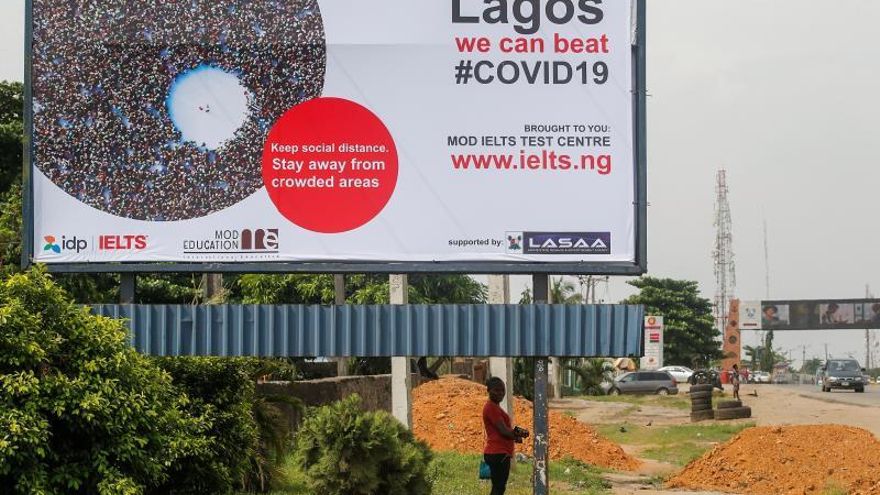 A woman stands under a billboard with a message on the prevention of the coronavirus along the Lagos-Ibadan expressway, in Lagos, Nigeria.