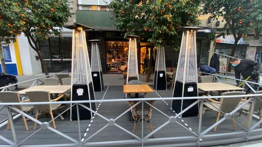 Veladores ubicados sobre una plataforma ocupando plazas de aparcamiento.