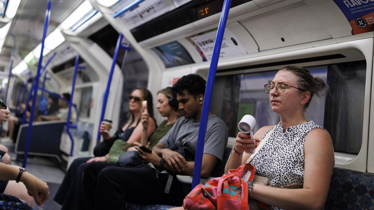 Pasajeros en el metro de Londres con mini-ventiladores este miércoles.