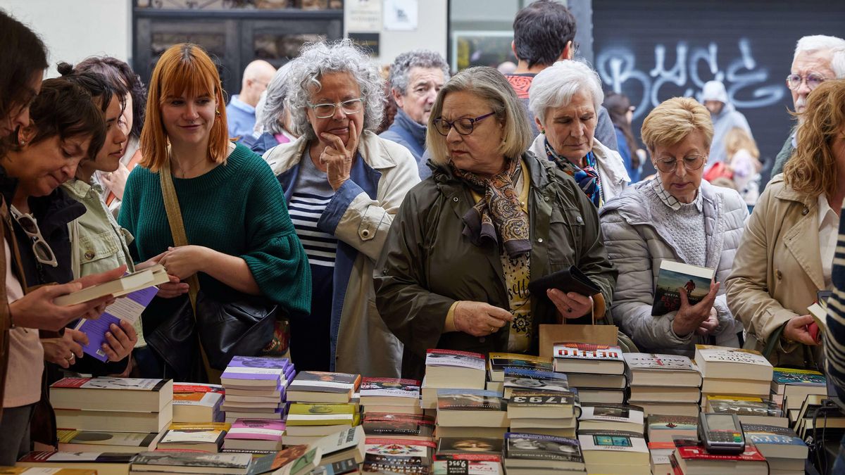 Varias personas miran libros en un puesto instalado por el Día del Libro.