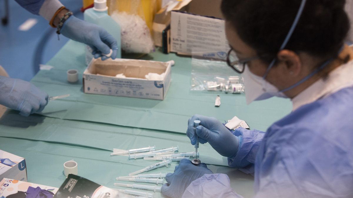 Una profesional sanitaria sostiene una jeringuilla con un vial de la vacuna contra la COVID-19 de AstraZeneca en un dispositivo de vacunación en el pabellón SADUS en Sevilla (Andalucía, España), a 24 de marzo de 2021.