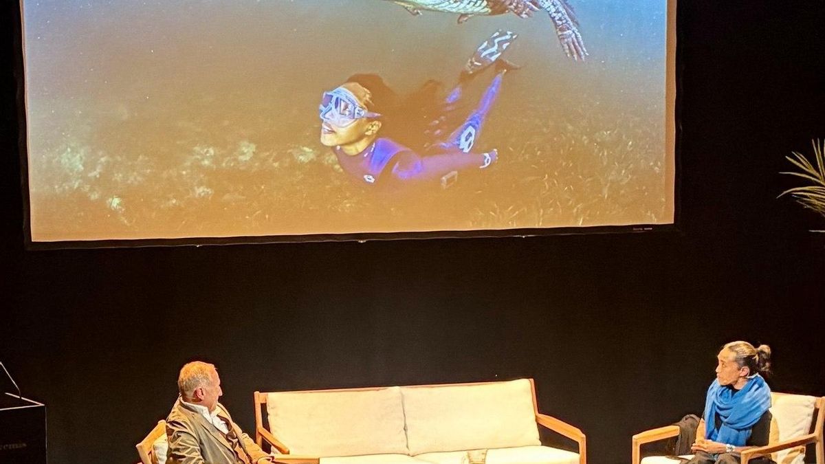 Ai Futaki en conversación con Michel André. En la pantalla, Ai bucea junto a un cocodrilo en el caribe cubano.