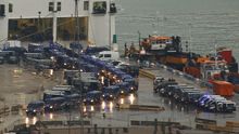 Vehículos policiales abandonan el puerto donde están alojados los agentes a primera hora del domingo.