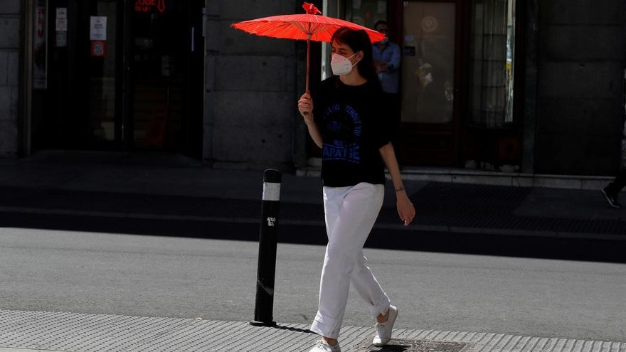 Una mujer se protege del sol con una sombrilla en el centro de Madrid.