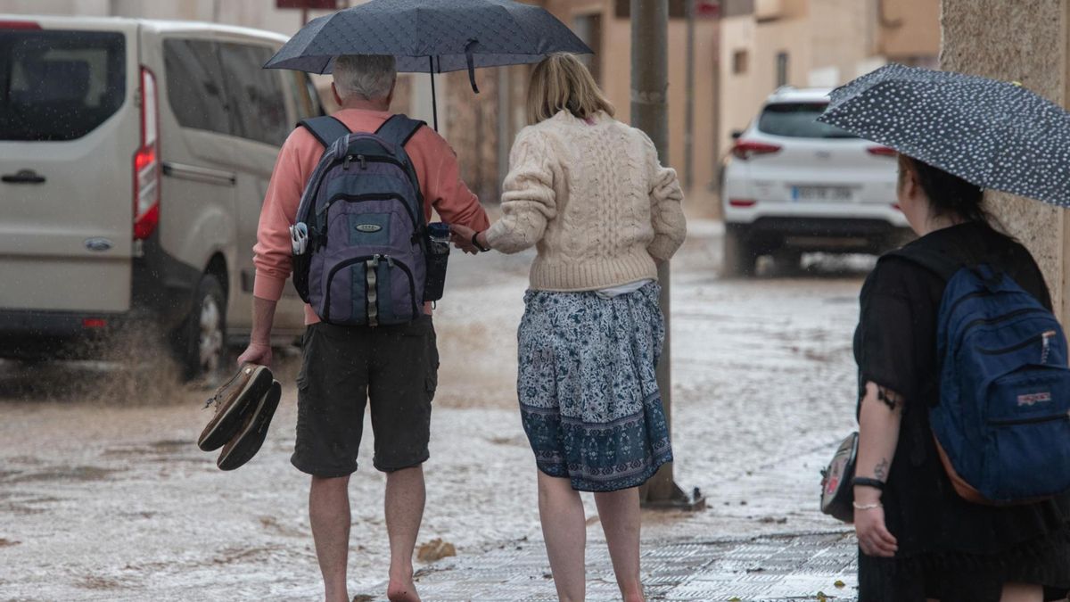 Varios turistas se protegen de la lluvia caída este sábado en Puerto del Rosario, Fuerteventura.