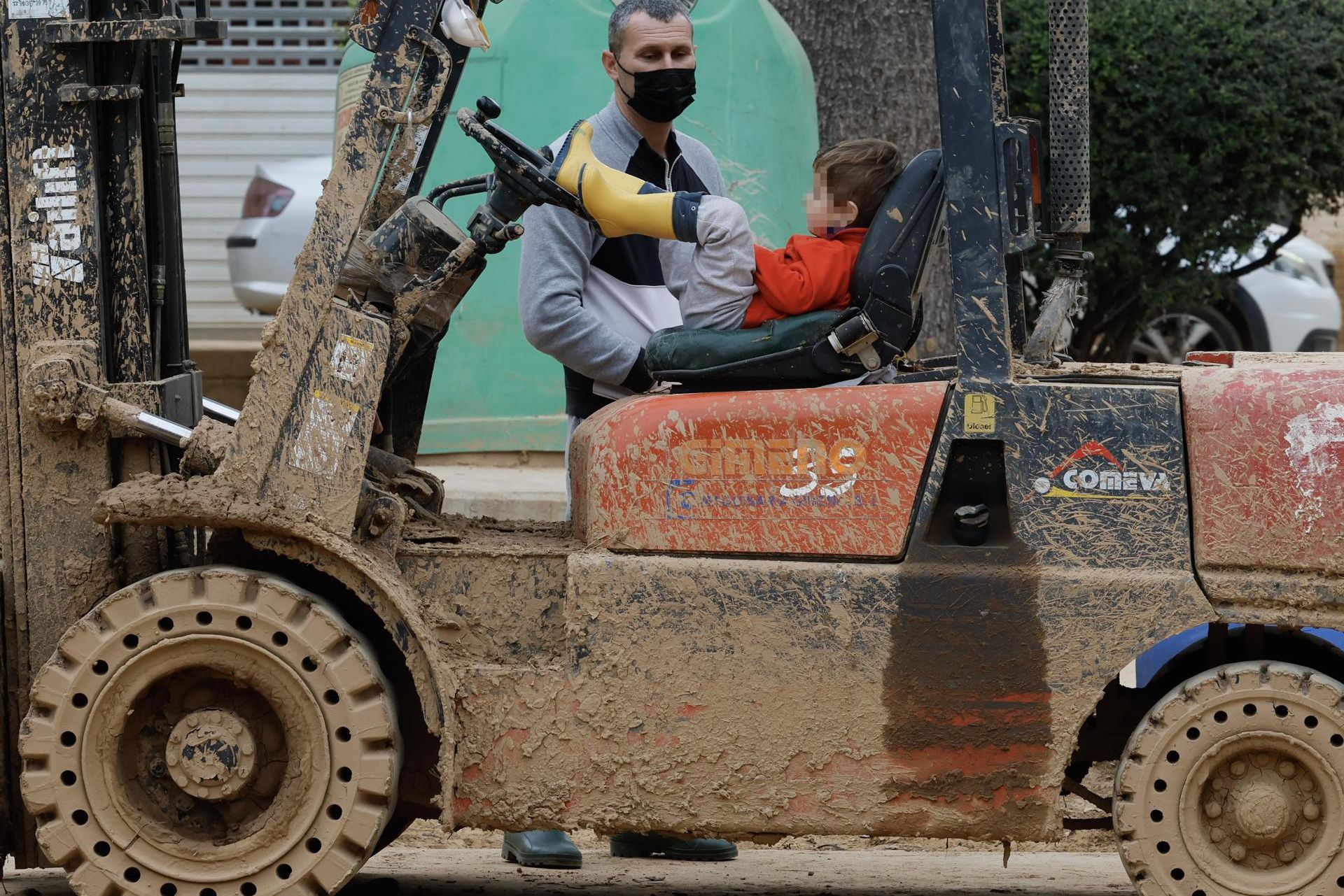 Un niño apoyado en una máquina de las utilizadas en las labores de limpieza del lodo este lunes en Massanassa.