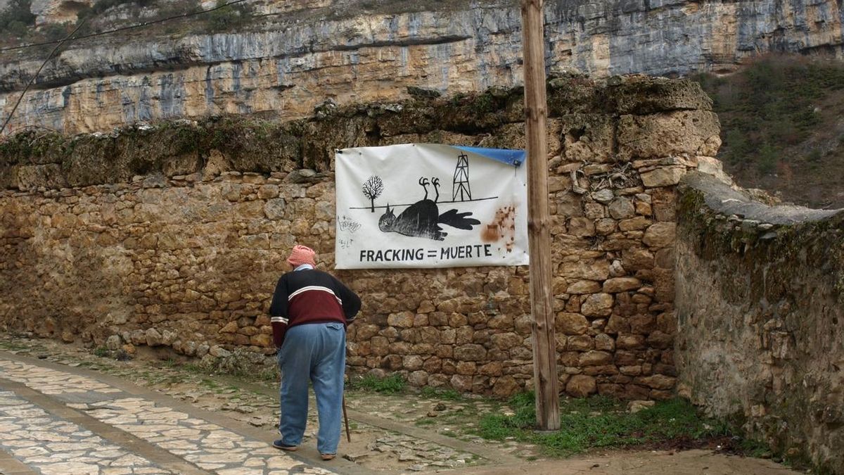 Un vecino camina delante de un cartel contra el uso del fracking en Cantabria.