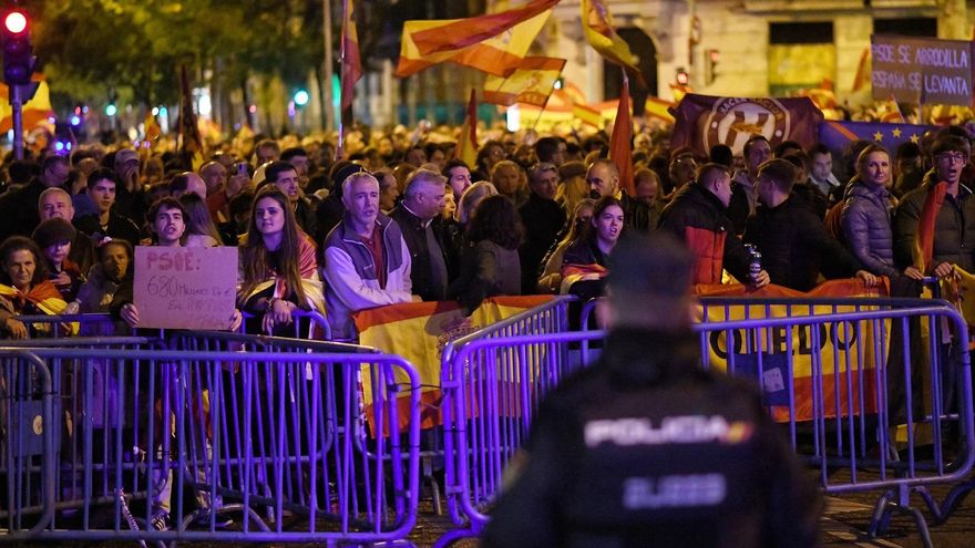 Decenas de personas con banderas y carteles, durante una protesta contra la amnistía, frente a la sede del PSOE, a 11 de noviembre de 2023, en Madrid (España)