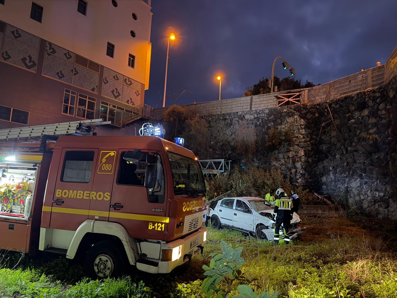 Un camión de Bomberos La Palma junto al coche  que se ha precipitado a  un solar desde una altura de unos 10 meros.