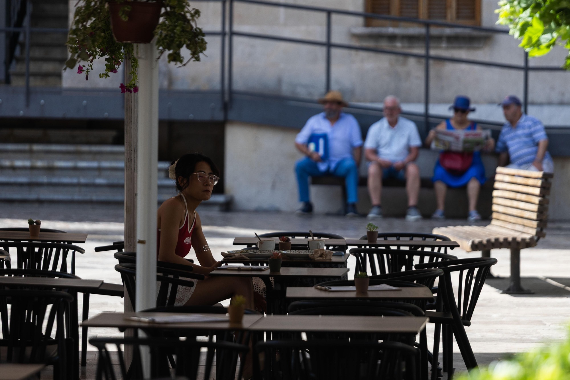 Una clienta treu el cap entre les taules buides d'una de les terrasses del centre de Sóller