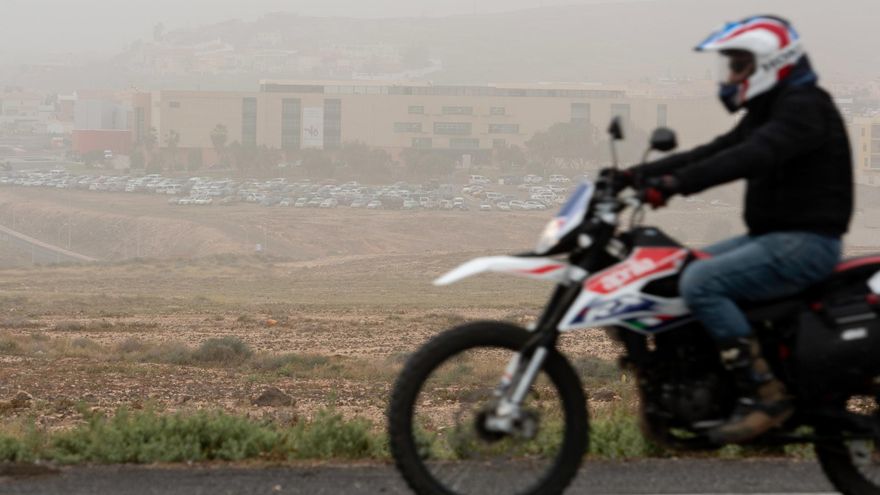 Un motorista circula por la carretera y se observa la alta presencia de calima
