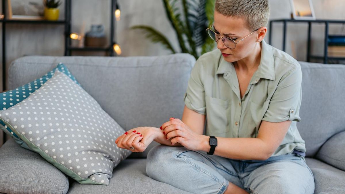 Mujer rascándose un brazo