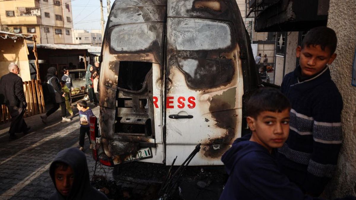 Palestinos junto a los restos de una furgoneta de la televisión Al-Quds Al-Youm atacada por Israel en Gaza, el 26 de diciembre de 2024.