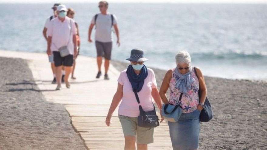 Personas con mascarilla en una playa de Canarias