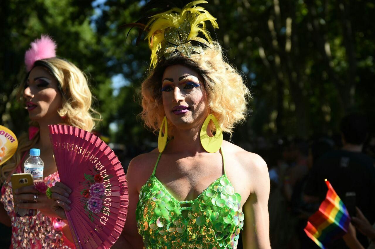 Una mujer aplaca el calor con un abanico en el desfile del Orgullo