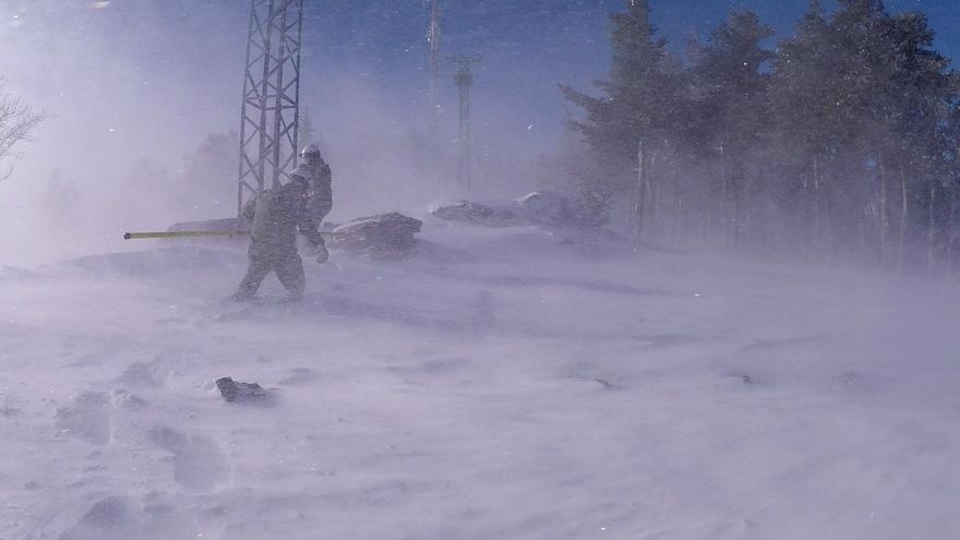 Dos operarios realizan trabajos de mantenimiento en la Sierra de Madrid bajo un temporal de nieve.
