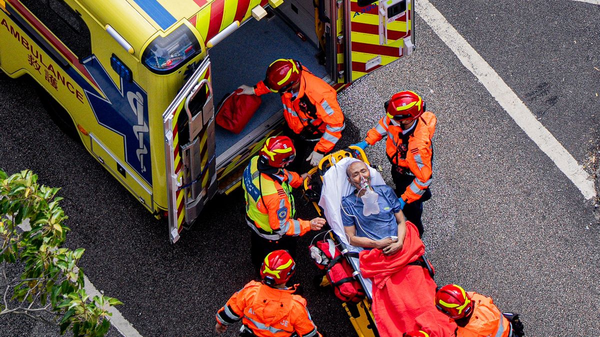 Servicios de emergencia suben a una persona herida en el incendio de Hong Kong a una ambulancia.