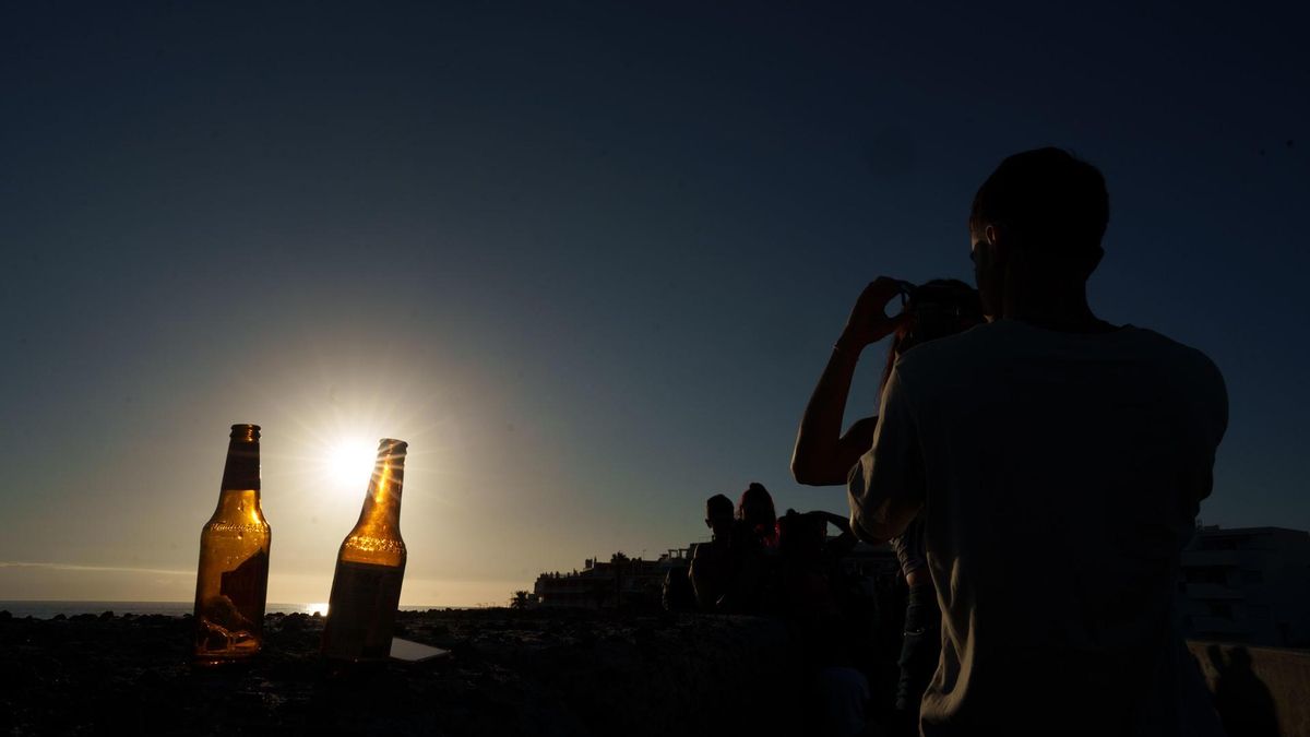 Varias personas contemplan desde la playa el eclipse solar, que se ha visto de forma parcial, este miércoles en el municipio tinerfeño de Guía de Isora.