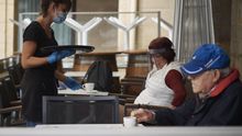 Una camarera atiende a varias personas sentadas en una terraza de Navarra donde los empleados utilizan un metro para asegurarse de que las medidas de distanciamiento son las correctas entre los potenciales clientes de la terraza de un bar en el centro de Pamplona, Navarra (España), durante el día 60 del estado de alarma, a 13 de mayo de 2020.