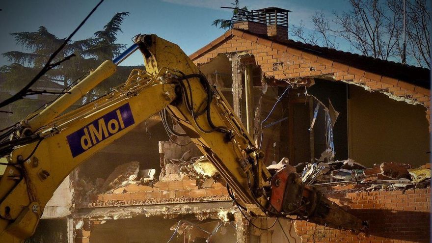 Una de las viviendas afectadas junto a la grúa que trabaja en su demolición