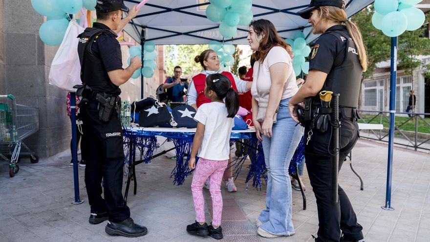 Dos agentes colaboran con la Fundación Madrina en la entrega de un kit completo de material escolar a los niños.