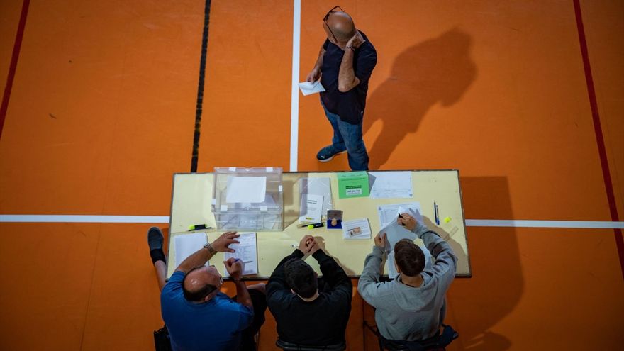 Un hombre espera a que los componentes de la mesa electoral comprueben su identidad para votar en Barcelona.
