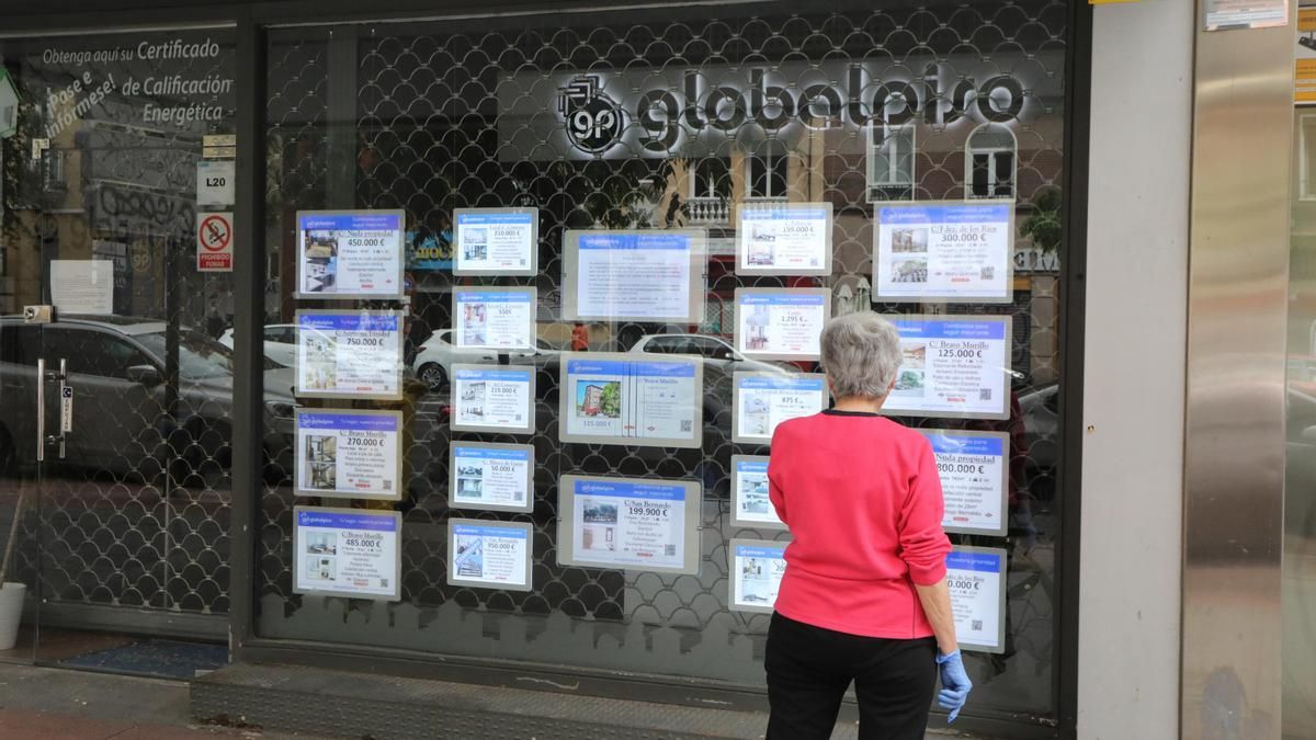 Una mujer echa un vistazo a las ofertas de una agencia inmobiliaria.