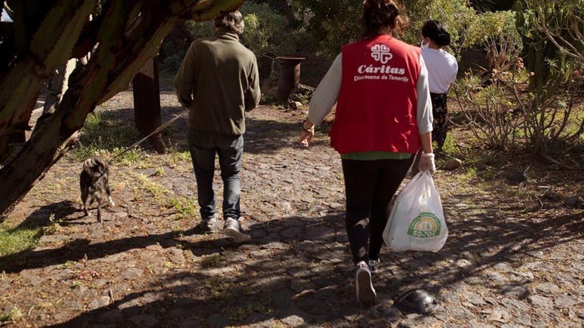 Una trabajadora social de Acción Social de Cáritas en Tenerife distribuye comida a personas sin hogar